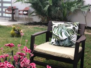 a chair with a pillow in a yard with flowers at Luxury Private Pool Villa for families only in Sanad