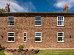 a brick building with white windows and flowers in a garden at The Hind House in Cowlam