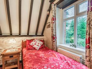 a bedroom with a red bed and a window at Colomendy Lodge in Corwen