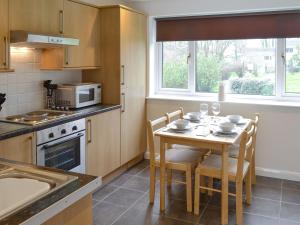 a kitchen with a table with chairs and a microwave at Newquay Holiday Villa in Saint Columb Major