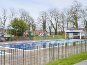 a pool in a park with a playground at Newquay Holiday Villa in Saint Columb Major