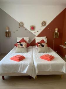 um quarto com 2 camas e lençóis vermelhos em Chambre d'hôtes Zephyr Libeccio Le Moulin de Prédelles em Reillanne