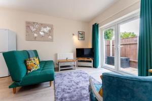 a living room with a green couch and a television at The Coastal Hideaway in Bournemouth