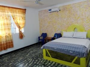 a bedroom with a bed and chairs and a window at Ndiro Beach House Kendwa in Kendwa