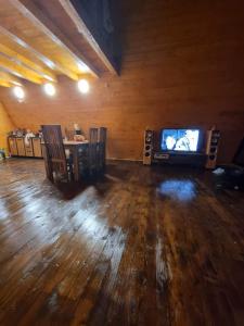 a living room with a tv and a wooden floor at Cabana Corbilor The Raven's Hut in Vatra Dornei