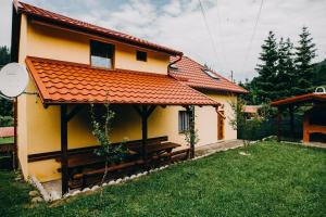 a yellow house with an orange roof with a bench at Casa Roland in Gheorgheni +23 photos