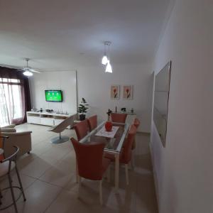 un soggiorno con tavolo, sedie e TV di Apartamento próximo a praia - Enseada Guarujá a Guarujá