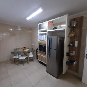 una cucina con tavolo e frigorifero in acciaio inossidabile di Apartamento próximo a praia - Enseada Guarujá a Guarujá