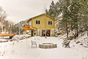 a yellow house in the snow with two chairs at Drake Home on Big Thompson River - 3 Mi to Estes! in Estes Park