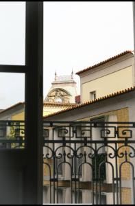 un bâtiment avec une tour d'horloge derrière une clôture dans l'établissement Rua das Flores Neighborhood, à Porto