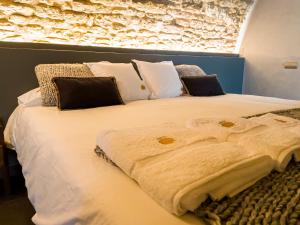 ein großes Bett mit weißer Bettwäsche und Kissen in der Unterkunft Masia de Queralt Luxury Casa Rural Spa y Vistas in Concabella