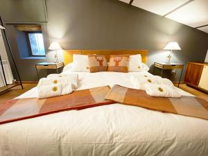 1 dormitorio con 1 cama blanca grande y toallas. en Masia de Queralt Luxury Casa Rural Spa y Vistas, en Concabella