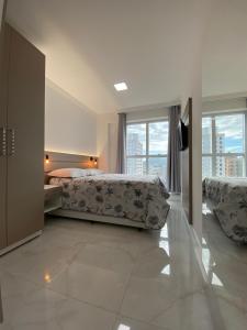 een slaapkamer met 2 bedden en een groot raam bij ACHOU! O melhor custo-benefício de Itapema! in Itapema