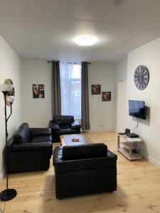 a living room with couches and a clock on the wall at Modern Apartment Third Floor in Brussels