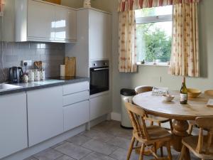 a kitchen with white cabinets and a table with chairs at Searchlight Cottage in Fraisthorpe