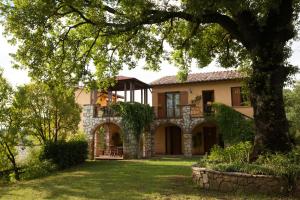 una grande casa con un albero nel cortile di Agriturismo La Vecchia Fattoria a Orte