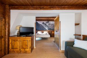 a living room with a television and a bedroom at Hotel Europa in Cortina dʼAmpezzo