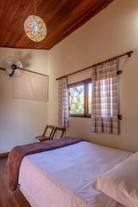 a bedroom with a large bed with a fan and a window at Pousada Lapralapa in Santana do Riacho