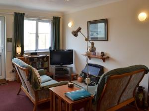 a living room with chairs and a table and a television at Scotties Retreat in Wrafton