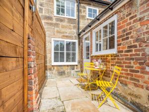 a patio with yellow chairs and a table in a brick building at The Twisted Toad in Guisborough