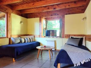 Habitación con cama, sofá y mesa. en Cabañas El Estribo Sur Bariloche en San Carlos de Bariloche
