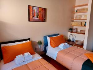 1 dormitorio con 2 camas con almohadas de color naranja en La Casa di Agata Deluxe, en Fucecchio