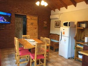 La cuisine est équipée d'une table, de chaises et d'un réfrigérateur. dans l'établissement Cabañas la Delfina, à Potrero de los Funes