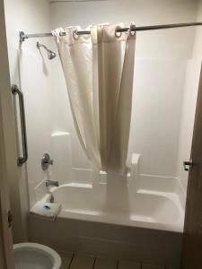 a bathroom with a tub and a toilet with a shower curtain at The Best Inn & Suites in Markham
