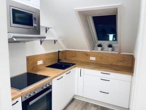 een keuken met witte kasten, een wastafel en een magnetron bij Apartment am Hohlbach in Gruibingen in Gruibingen