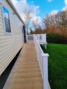 a wooden walkway with a bench on the side of a house at 31 solent village in Porchfield