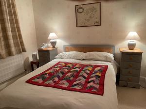 a bedroom with a bed with a red blanket on it at Silver Lodge Guest House in Mildenhall