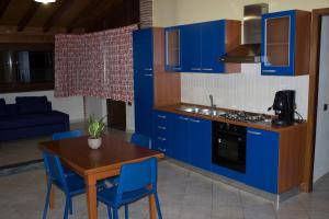 eine Küche mit blauen Schränken, einem Tisch und blauen Stühlen in der Unterkunft Casa Contemare in Viagrande