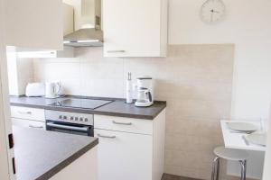uma cozinha com armários brancos e um forno com placa de fogão em Celler Appartement em Celle