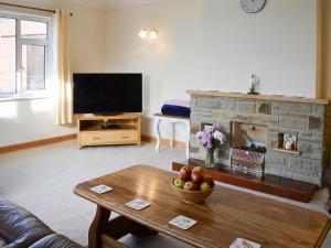 un soggiorno con TV e camino di Ivy Grange Cottage a Wistow