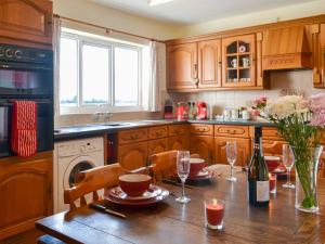 a kitchen with a table with a bottle of wine at Ivy Grange Cottage in Wistow