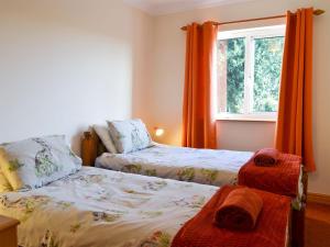 Wistow的住宿－Ivy Grange Cottage，一间卧室设有两张床,窗户配有橙色窗帘