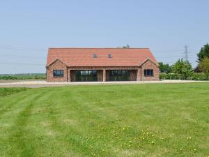 una casa de ladrillo con un campo de hierba delante de ella en Aimmees Lodge - Ukc2203 en Doddington