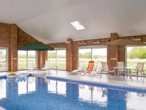 una piscina con sedie, tavoli e ombrelloni di Aimmees Lodge - Ukc2203 a Doddington