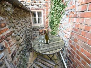 een fles wijn op een houten tafel in een bakstenen muur bij Cobble Cottage30c - Ukc2846 in Blakeney