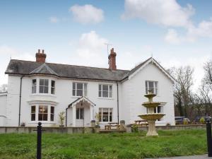 a white house with a fountain in front of it at Maesbangor Farmhouse in Capel Bangor