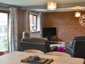 sala de estar con muebles de cuero y pared de ladrillo en Carp Cottage - Ukc1907 en Doddington