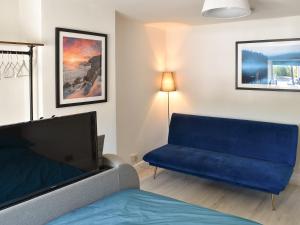 een woonkamer met een blauwe bank en een tv bij Morton Loft in Hathersage