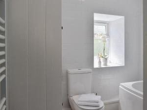 a white bathroom with a toilet and a window at Morton Loft in Hathersage