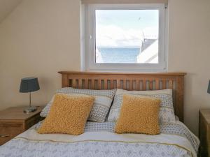um quarto com uma cama e uma janela grande em Rosslyn Cottage em Portmahomack