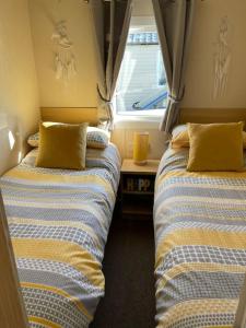 twee bedden naast elkaar in een kamer bij Lexi Lodge @ Littlesea Holiday Park, Weymouth in Wyke Regis