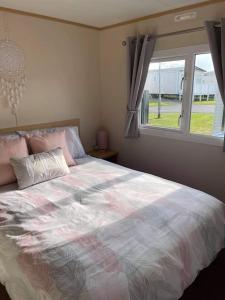 a bedroom with a large bed with a window at Lexi Lodge @ Littlesea Holiday Park, Weymouth in Wyke Regis