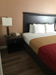 a hotel room with a bed with a lamp and a phone at The Best Inn & Suites in Markham