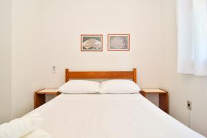 1 dormitorio con 1 cama con 2 almohadas blancas en 50 metros da Praia nos Ingleses, 4 hóspedes P1991, en Florianópolis