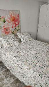 - un lit avec une couette et des oreillers à fleurs dans l'établissement PISABEL, à Sanlúcar de Barrameda
