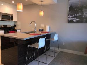 a kitchen with a sink and two bar stools at Amicable, Cozy, High Speed Internet, Sleeps 2 Riverview Downtown Apartment in Calgary